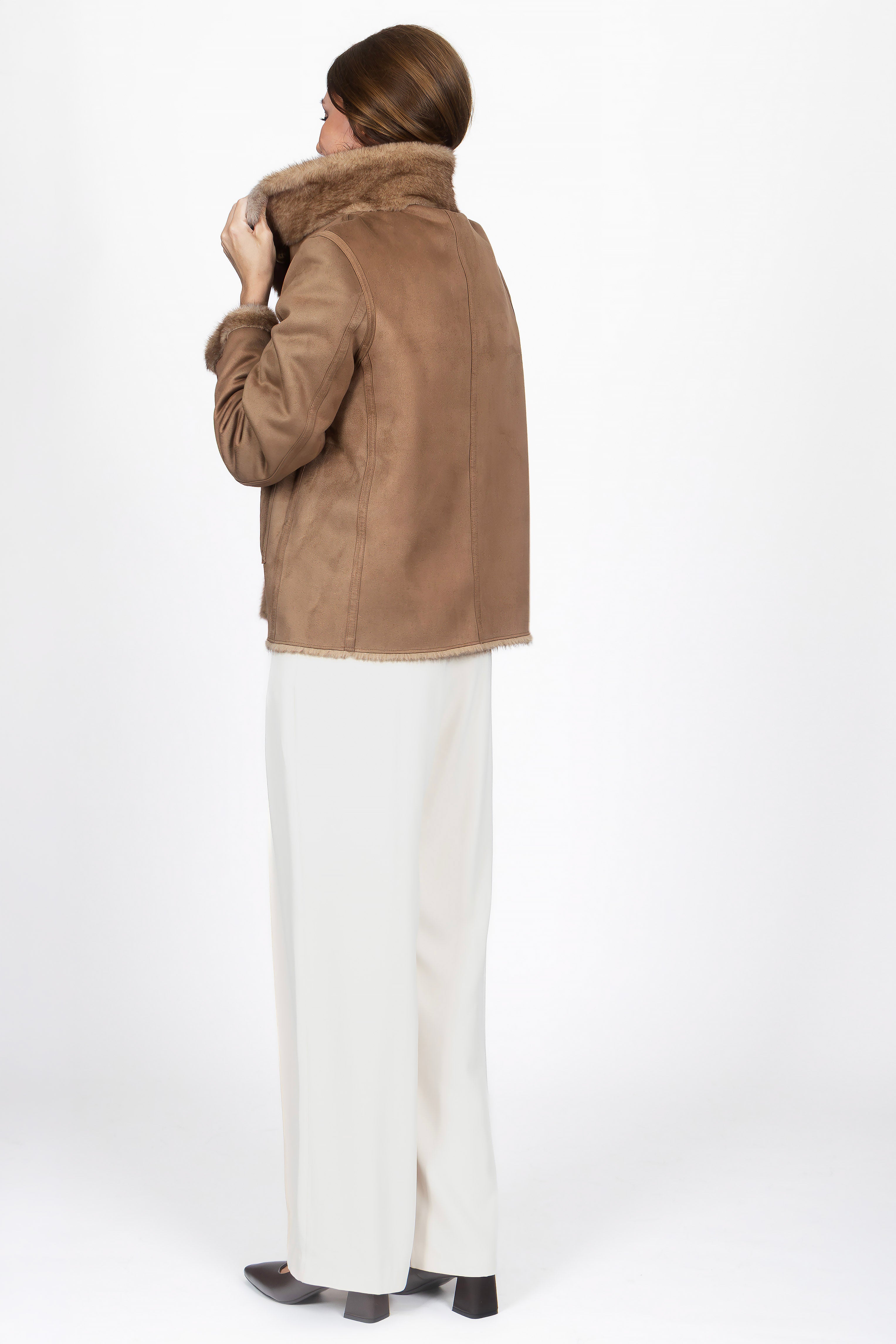 Model trägt eine kurze Damen-Wendejacke aus Kunstfell in Dunkelbraun mit Lammfell-Optik